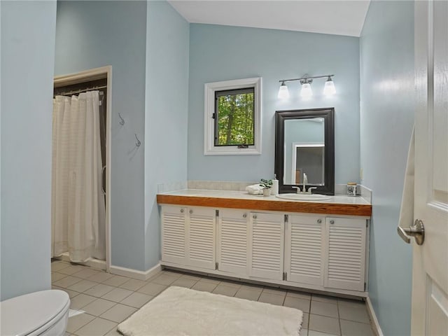 bathroom with tile patterned flooring, vanity, vaulted ceiling, and toilet