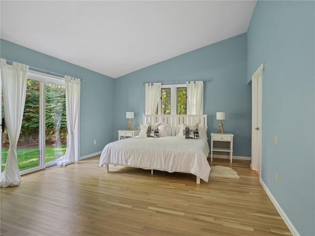 bedroom with light wood-type flooring, access to outside, and lofted ceiling