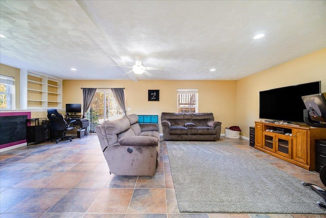 living room featuring ceiling fan, built in features, and a textured ceiling