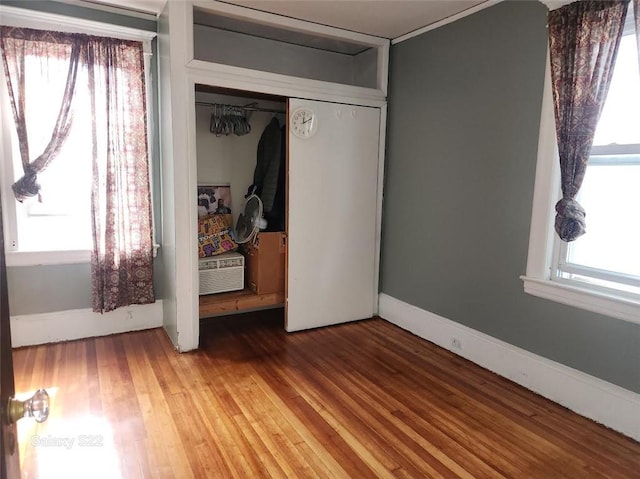 unfurnished bedroom featuring multiple windows, hardwood / wood-style flooring, and a closet