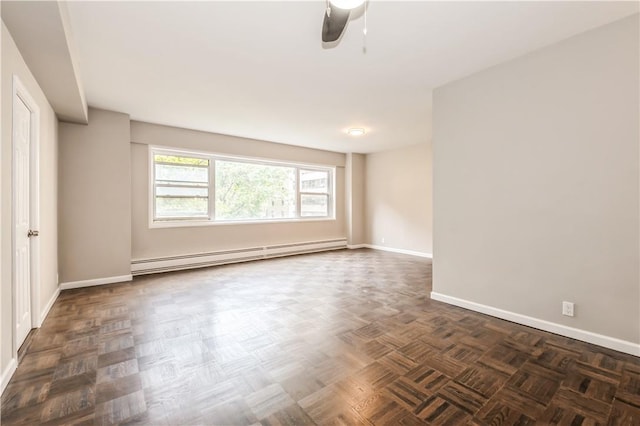 spare room featuring ceiling fan, dark parquet flooring, and a baseboard radiator