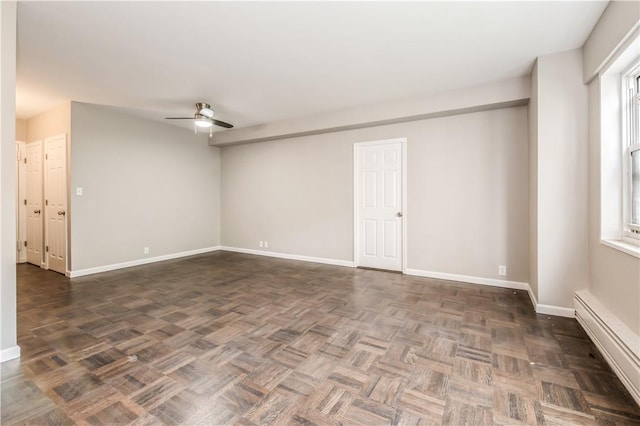 empty room featuring ceiling fan and a baseboard heating unit