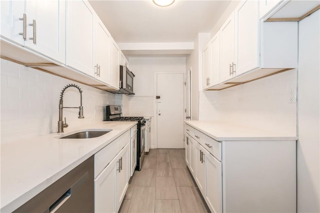 kitchen with backsplash, white cabinetry, sink, and appliances with stainless steel finishes