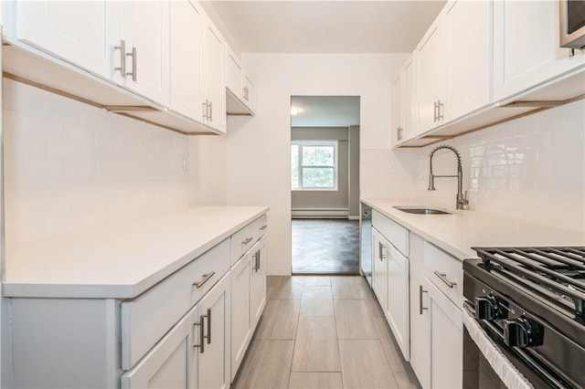 kitchen with white cabinets, light hardwood / wood-style floors, a baseboard heating unit, and sink