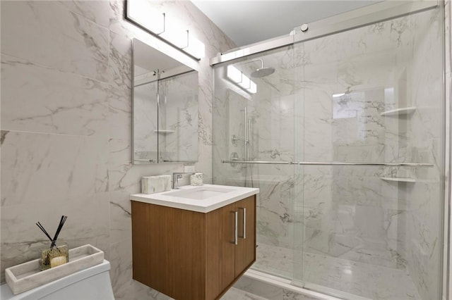 bathroom with vanity, toilet, a shower with door, and tile walls