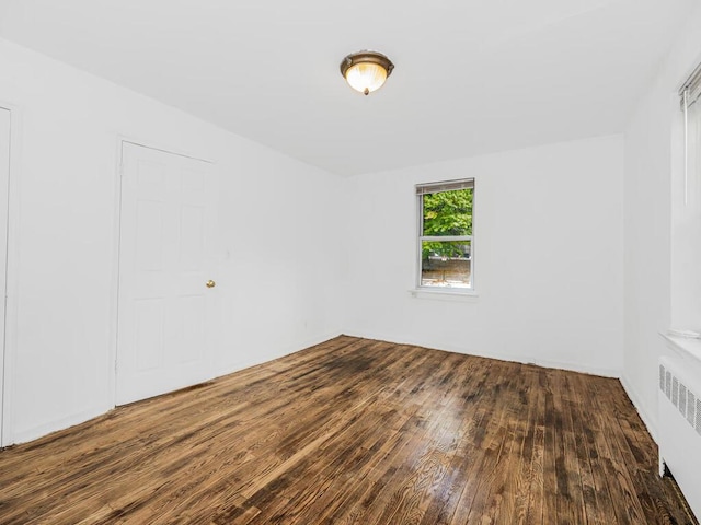 unfurnished room featuring radiator and dark hardwood / wood-style flooring