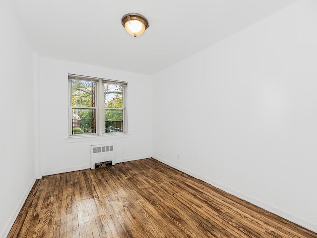 spare room with radiator heating unit and hardwood / wood-style flooring