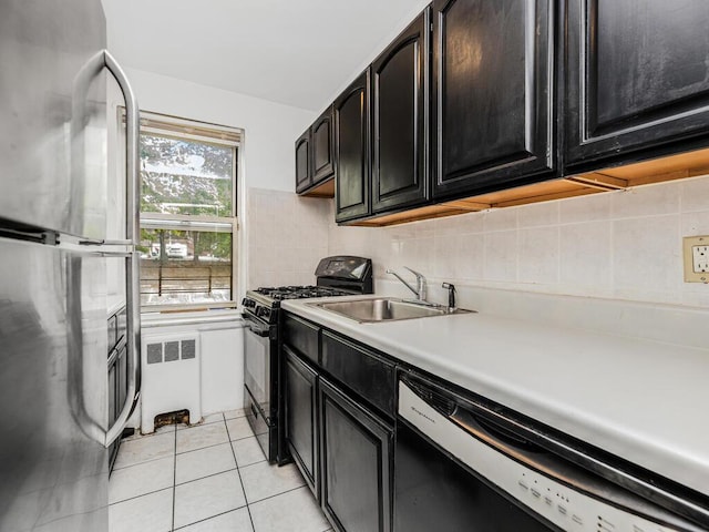 kitchen featuring decorative backsplash, appliances with stainless steel finishes, sink, light tile patterned floors, and radiator heating unit