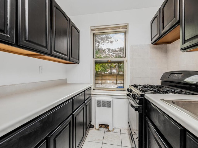 kitchen with tasteful backsplash, black range with gas stovetop, light tile patterned floors, and radiator