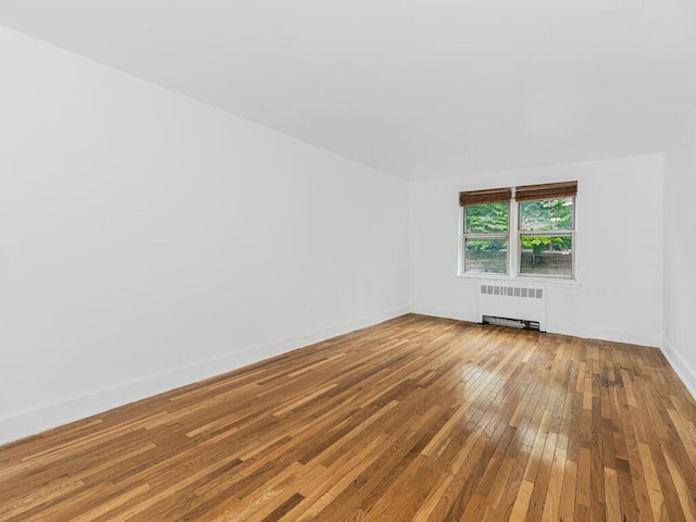 unfurnished room featuring radiator and wood-type flooring