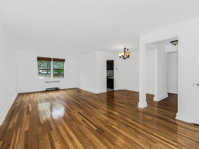 unfurnished living room with a chandelier, radiator heating unit, and dark wood-type flooring