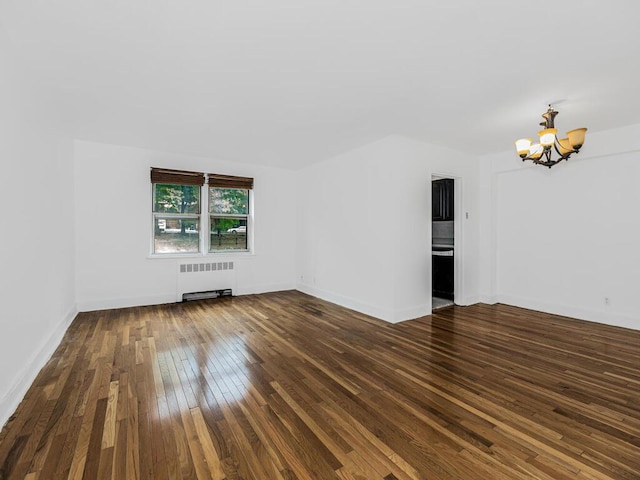 empty room featuring dark hardwood / wood-style flooring, radiator heating unit, and an inviting chandelier