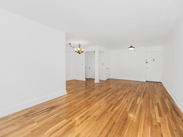 unfurnished living room with light hardwood / wood-style flooring and an inviting chandelier