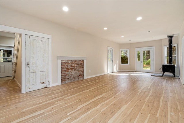 unfurnished living room with a wood stove and light wood-type flooring