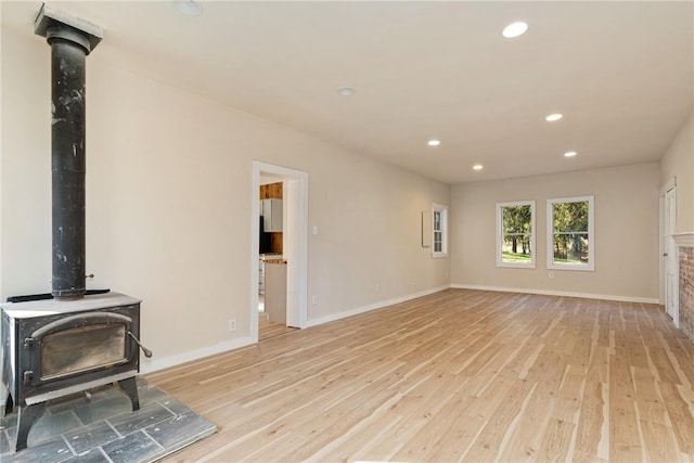 unfurnished living room featuring light hardwood / wood-style flooring and a wood stove