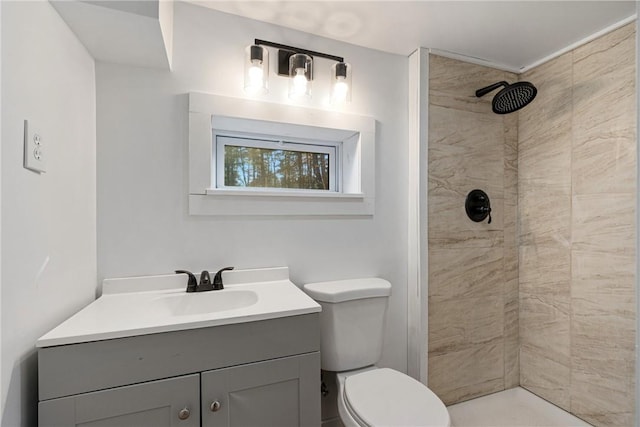 bathroom with a tile shower, vanity, and toilet