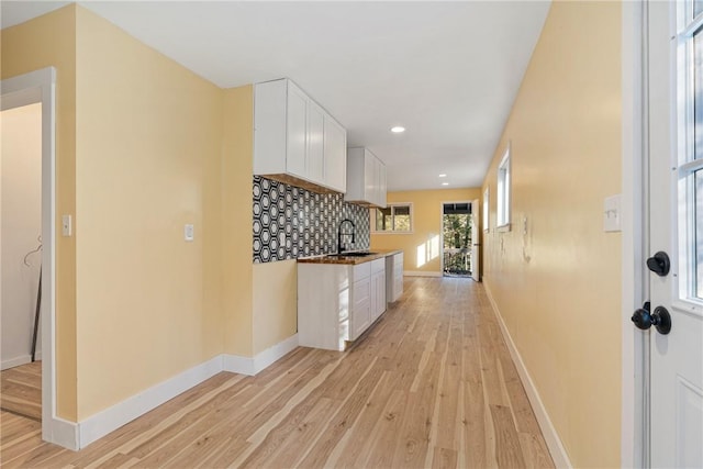 kitchen with decorative backsplash, light hardwood / wood-style floors, white cabinetry, and sink