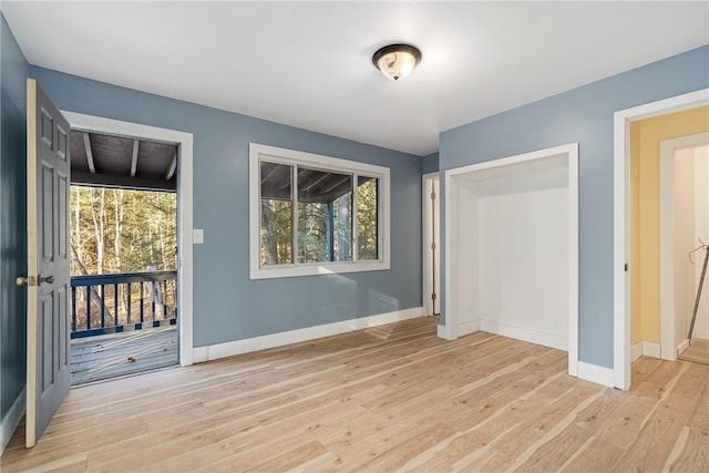 unfurnished bedroom with a closet, access to exterior, light wood-type flooring, and multiple windows