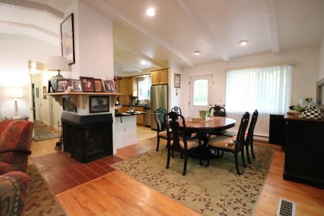 dining space featuring lofted ceiling with beams, light hardwood / wood-style floors, and baseboard heating