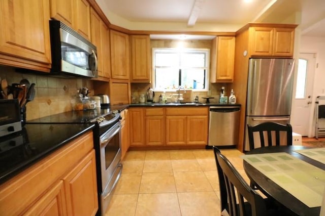 kitchen featuring decorative backsplash, sink, light tile patterned floors, and stainless steel appliances