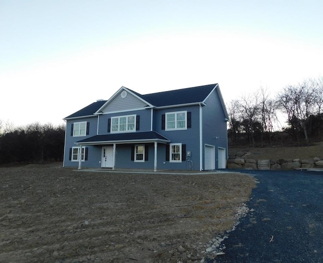 view of property with a porch and a garage