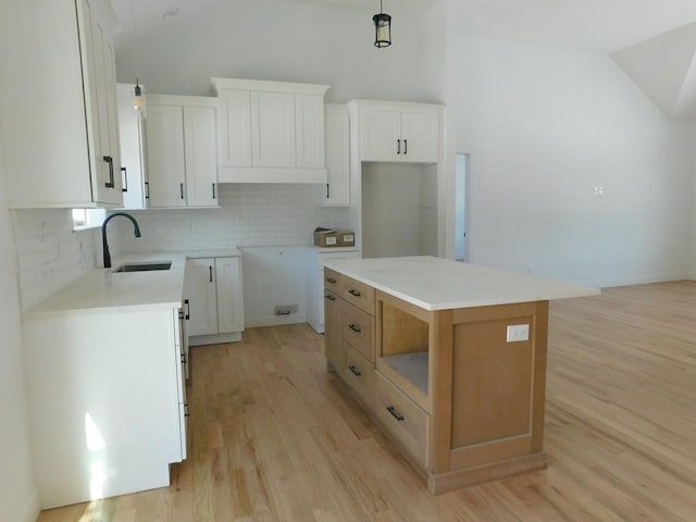 kitchen featuring sink, a center island, decorative backsplash, and white cabinetry