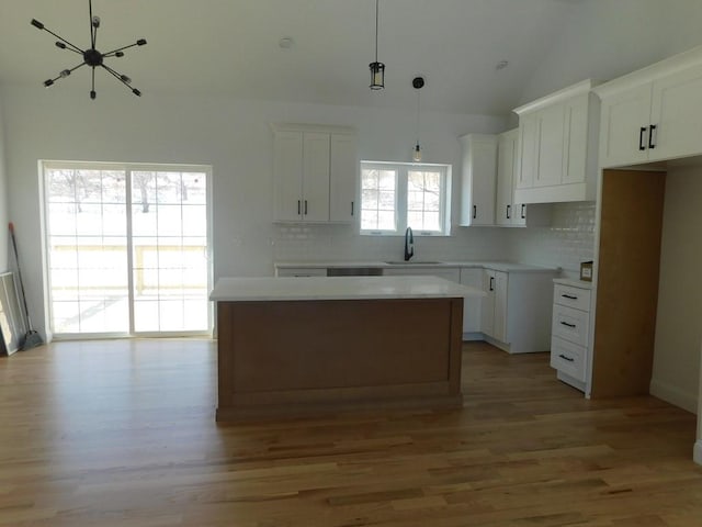 kitchen with pendant lighting, sink, white cabinetry, tasteful backsplash, and a kitchen island