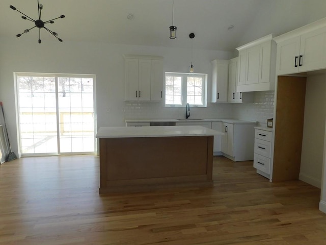 kitchen featuring white cabinets, a center island, hanging light fixtures, and light hardwood / wood-style flooring