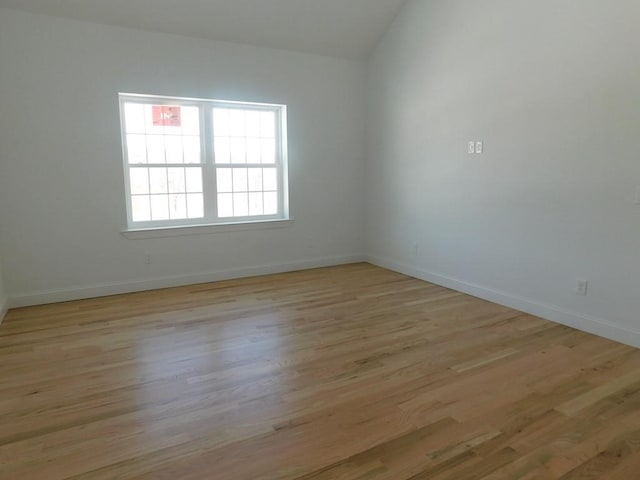 spare room with light hardwood / wood-style flooring and vaulted ceiling