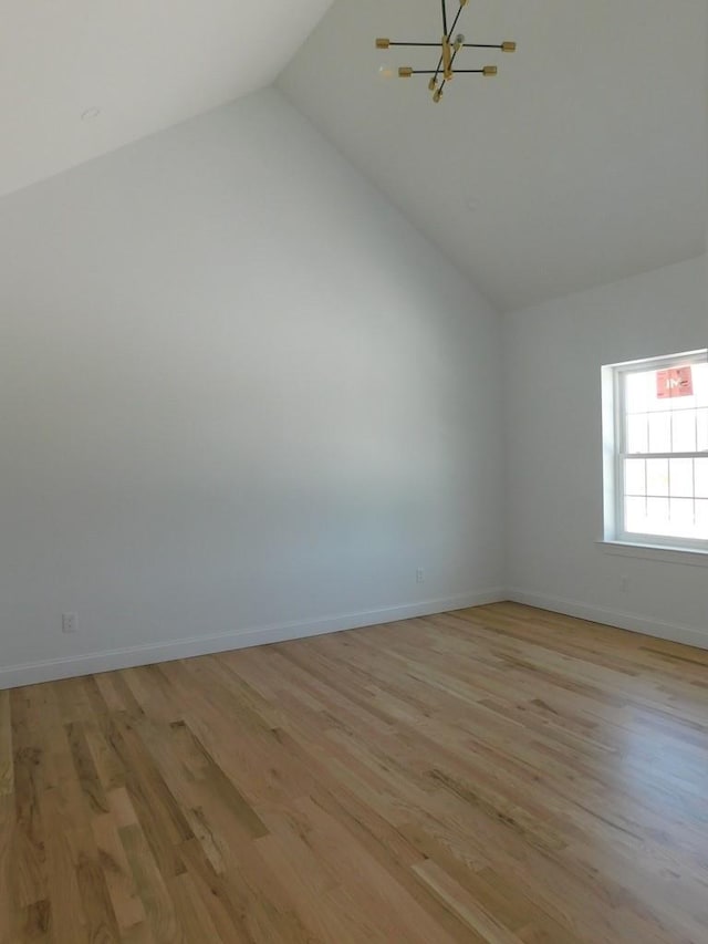 spare room with light hardwood / wood-style floors, lofted ceiling, and a notable chandelier