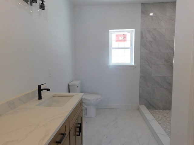 bathroom with vanity, toilet, tiled shower, and tile patterned flooring