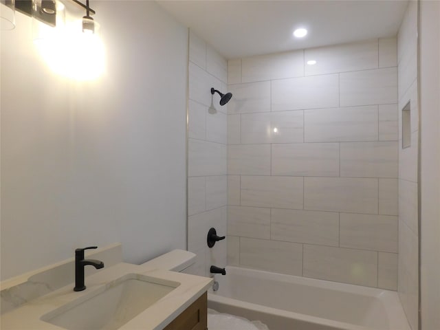 full bathroom with toilet, tiled shower / bath, and vanity