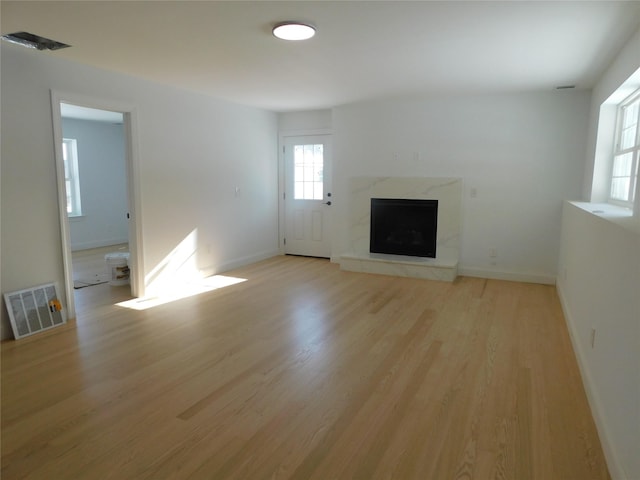 unfurnished living room with a high end fireplace and light wood-type flooring