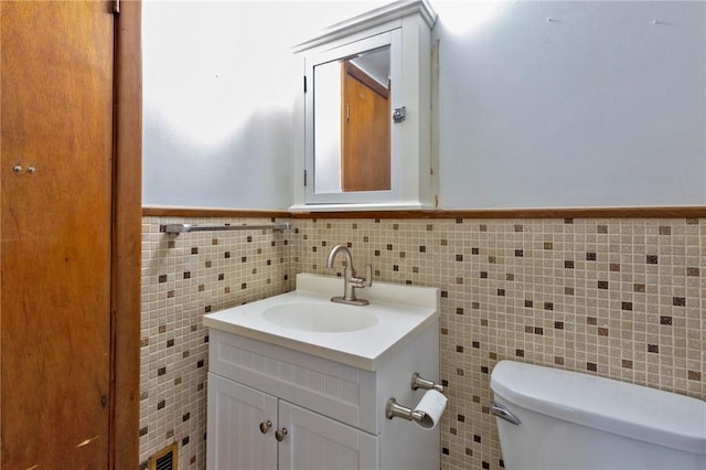 bathroom featuring vanity, tile walls, and toilet