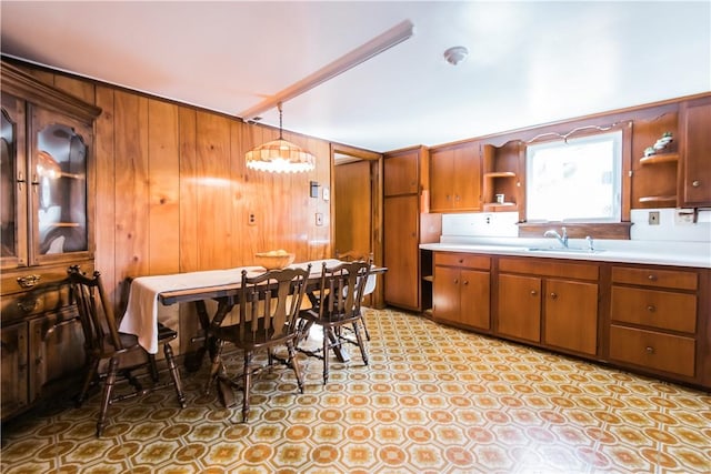 kitchen with wood walls, sink, and pendant lighting