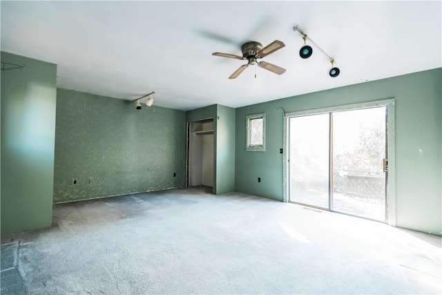 carpeted empty room featuring ceiling fan and track lighting