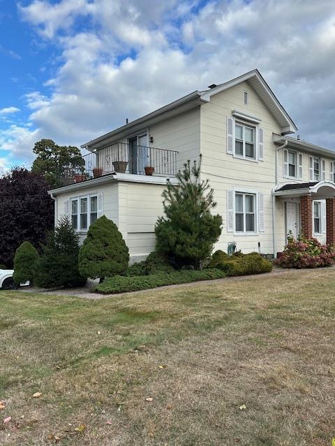 view of property exterior featuring a lawn and a balcony