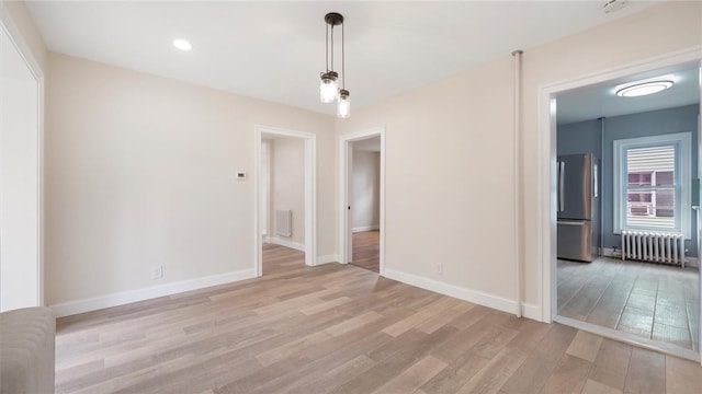 spare room with light hardwood / wood-style floors and radiator