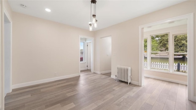 empty room with light hardwood / wood-style floors and radiator