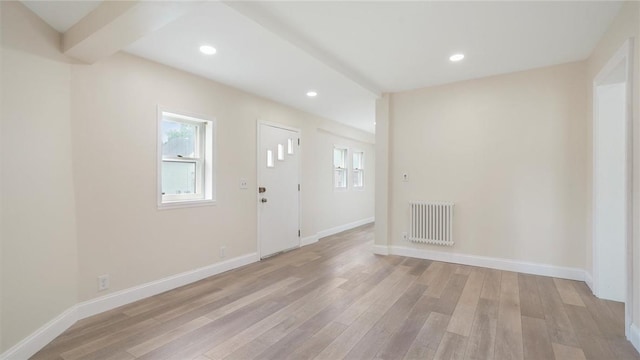 entrance foyer featuring beam ceiling, radiator heating unit, and light hardwood / wood-style floors