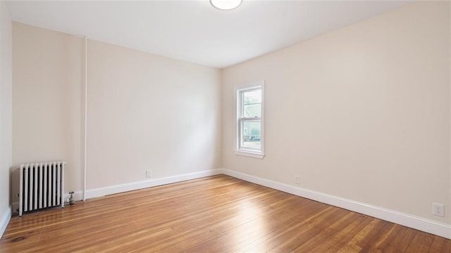 spare room featuring wood-type flooring and radiator