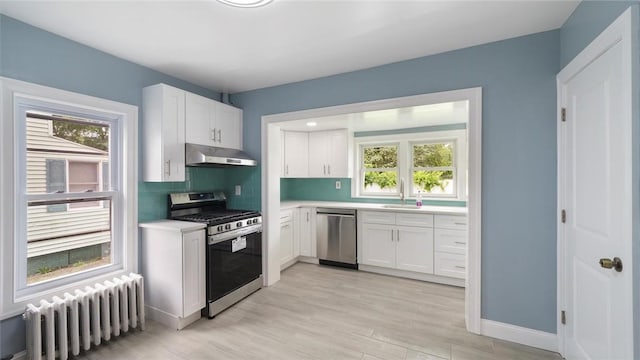 kitchen featuring a healthy amount of sunlight, white cabinetry, stainless steel appliances, and radiator