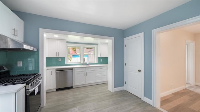 kitchen with backsplash, stainless steel appliances, sink, light hardwood / wood-style flooring, and white cabinetry