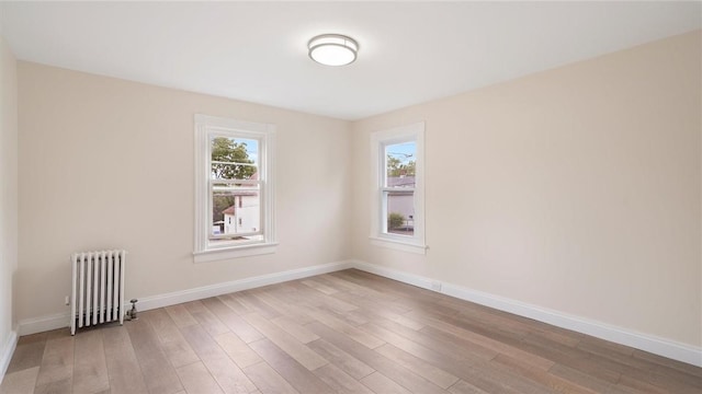 empty room featuring radiator heating unit and light hardwood / wood-style flooring