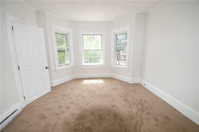 carpeted empty room featuring ornamental molding, baseboard heating, and a wealth of natural light