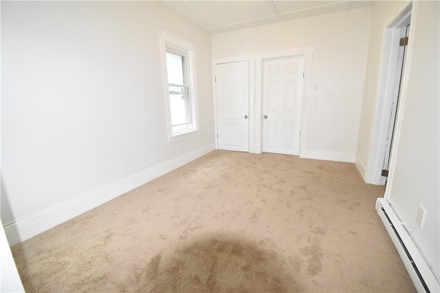 unfurnished bedroom with light colored carpet and a baseboard heating unit