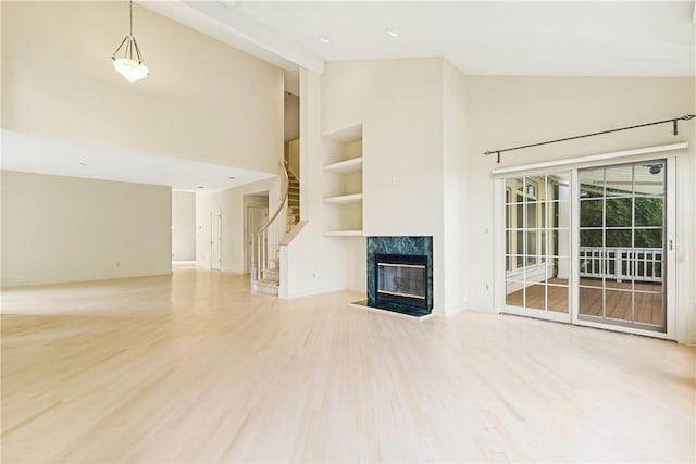 unfurnished living room featuring a premium fireplace, hardwood / wood-style floors, and high vaulted ceiling