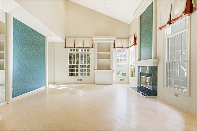 unfurnished living room featuring light wood-type flooring, high vaulted ceiling, and a premium fireplace