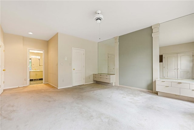 unfurnished bedroom with ceiling fan, light carpet, and connected bathroom