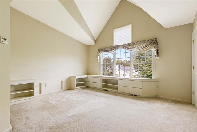 carpeted spare room featuring high vaulted ceiling